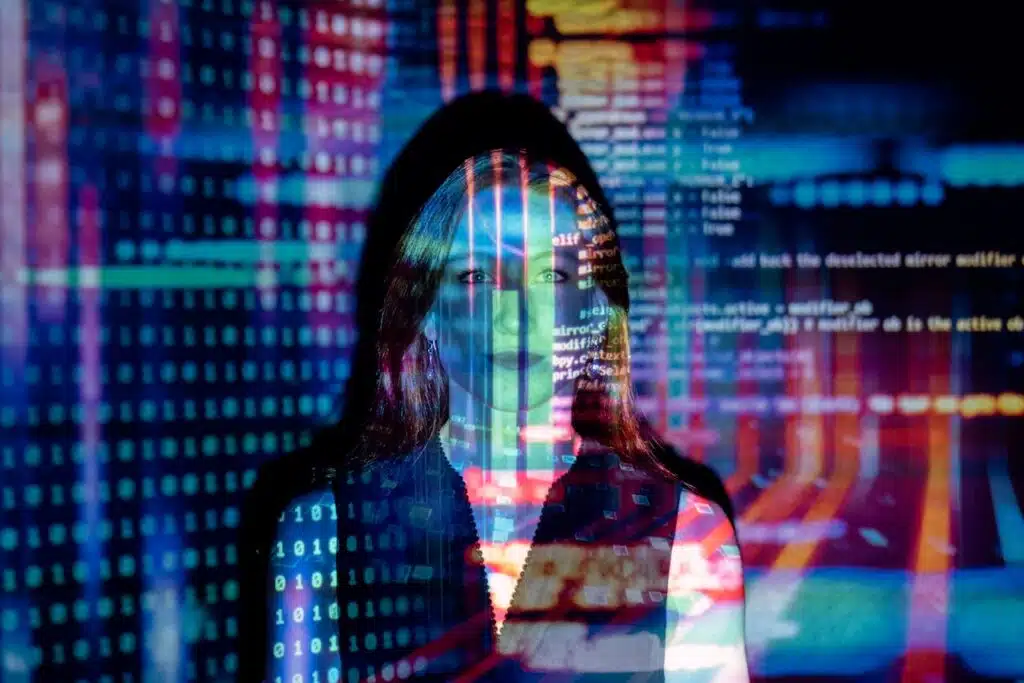 Woman standing in dim light with text projected onto her body and face.