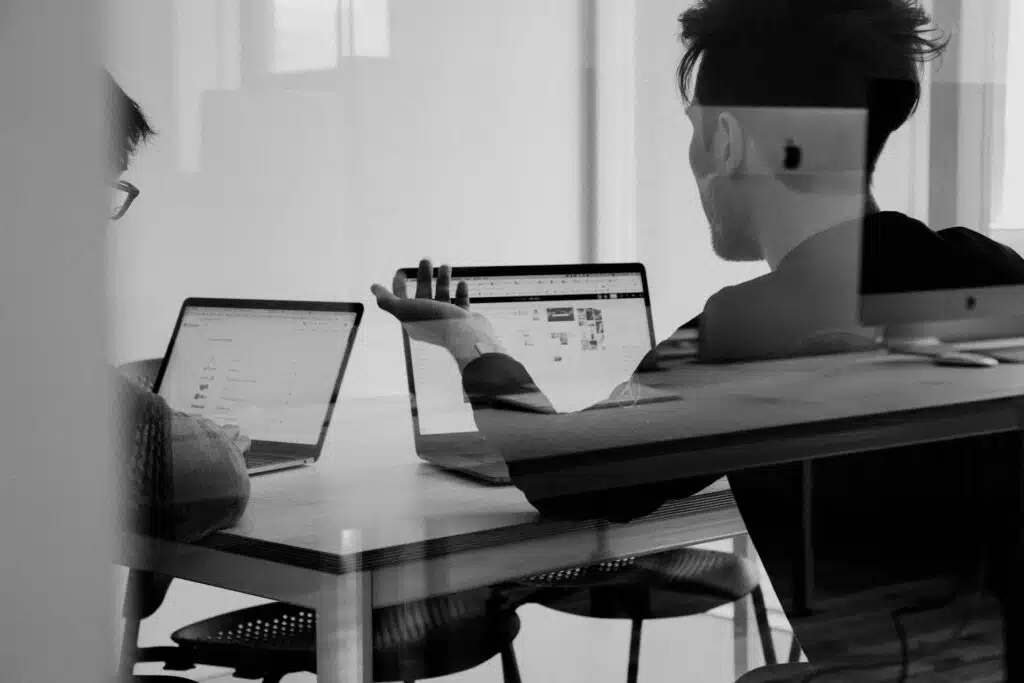 two men with laptop talking to each other